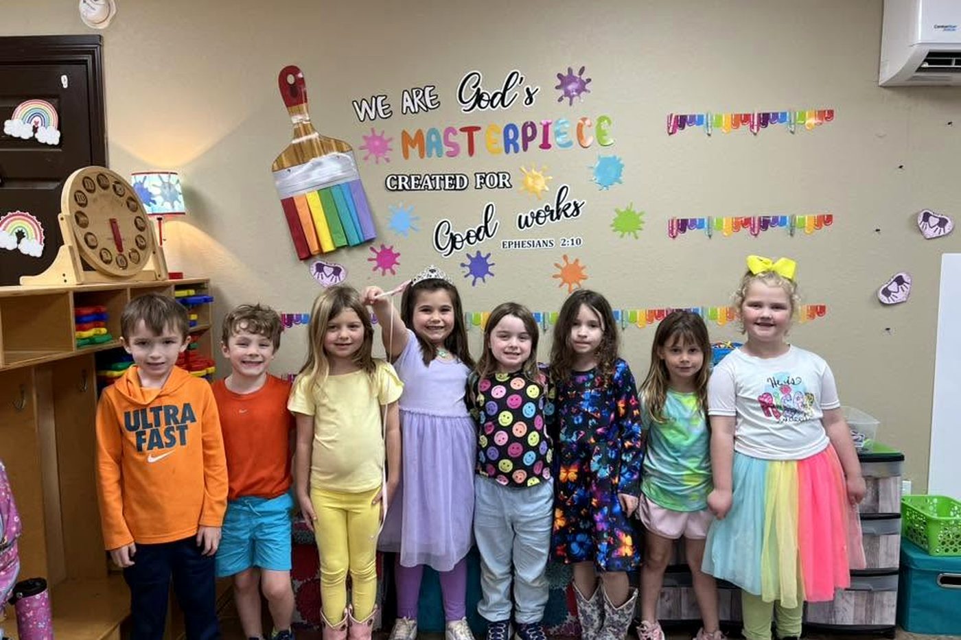 Pre-K students in front of a We Are God's Masterpiece wall display
